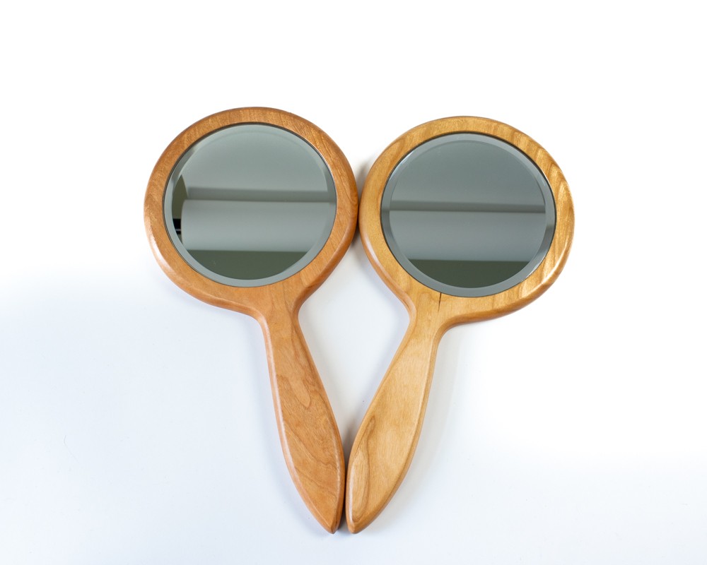 Photo of two hand mirrors in cherry with the mirror facing up.