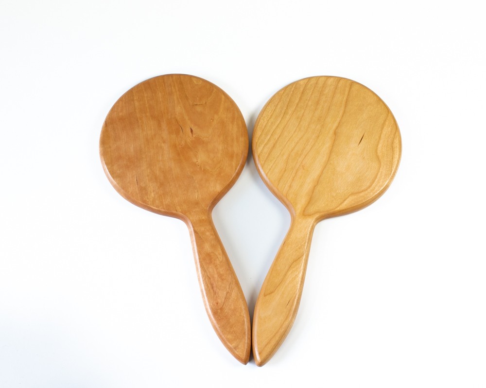 Photo of two hand mirrors in cherry with the mirror facing down.